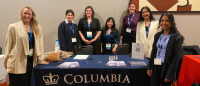 students posing in front of conference tabletop